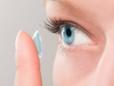 Woman inserting a contact lens in her eye.